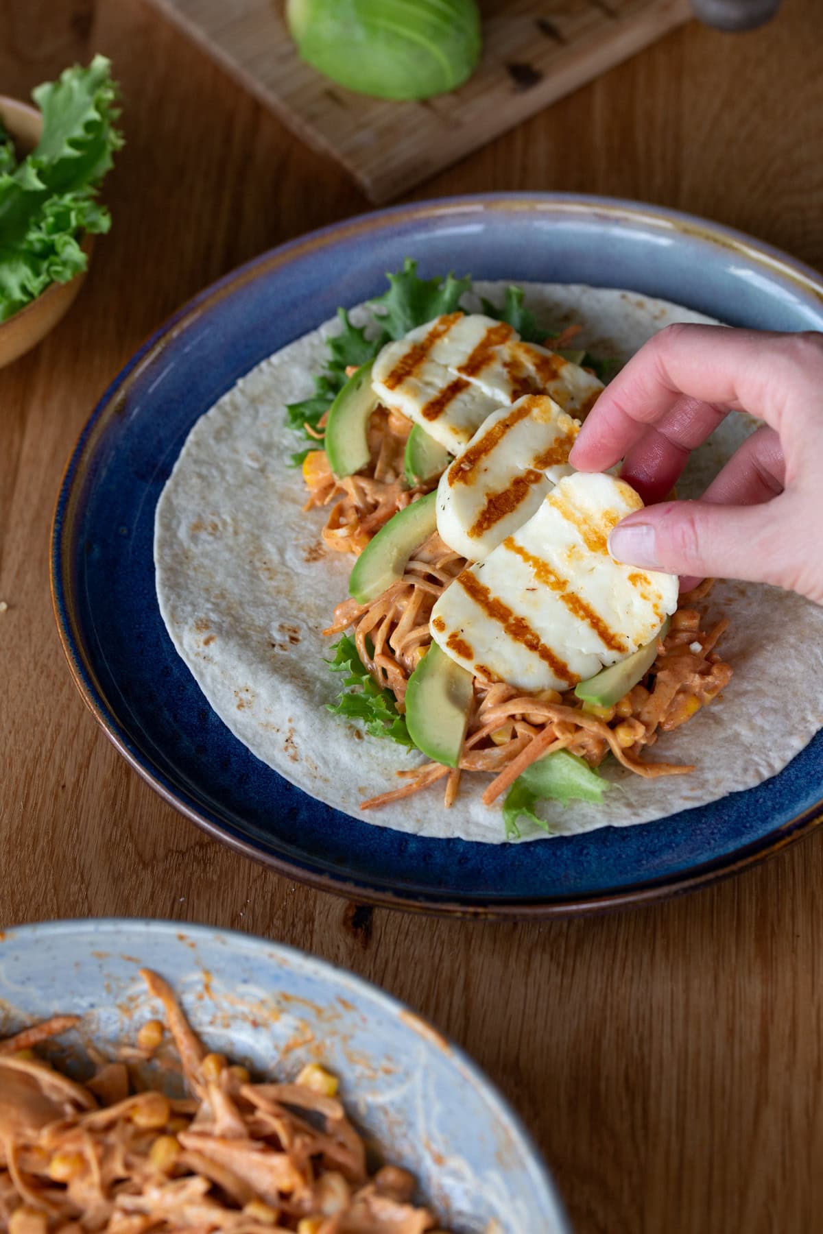Hand adding grilled halloumi to wrap.