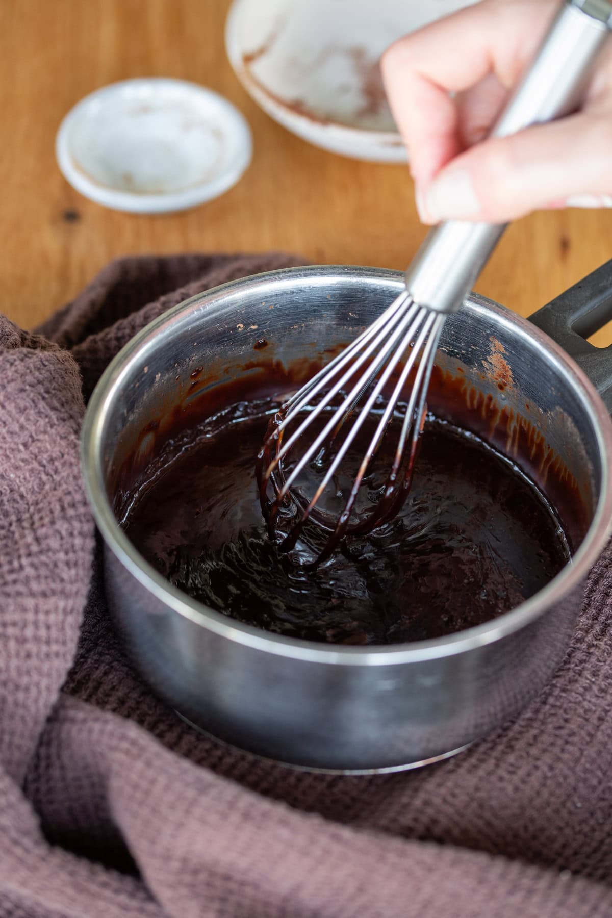 Hand whisking cocoa and coffee in small pot,