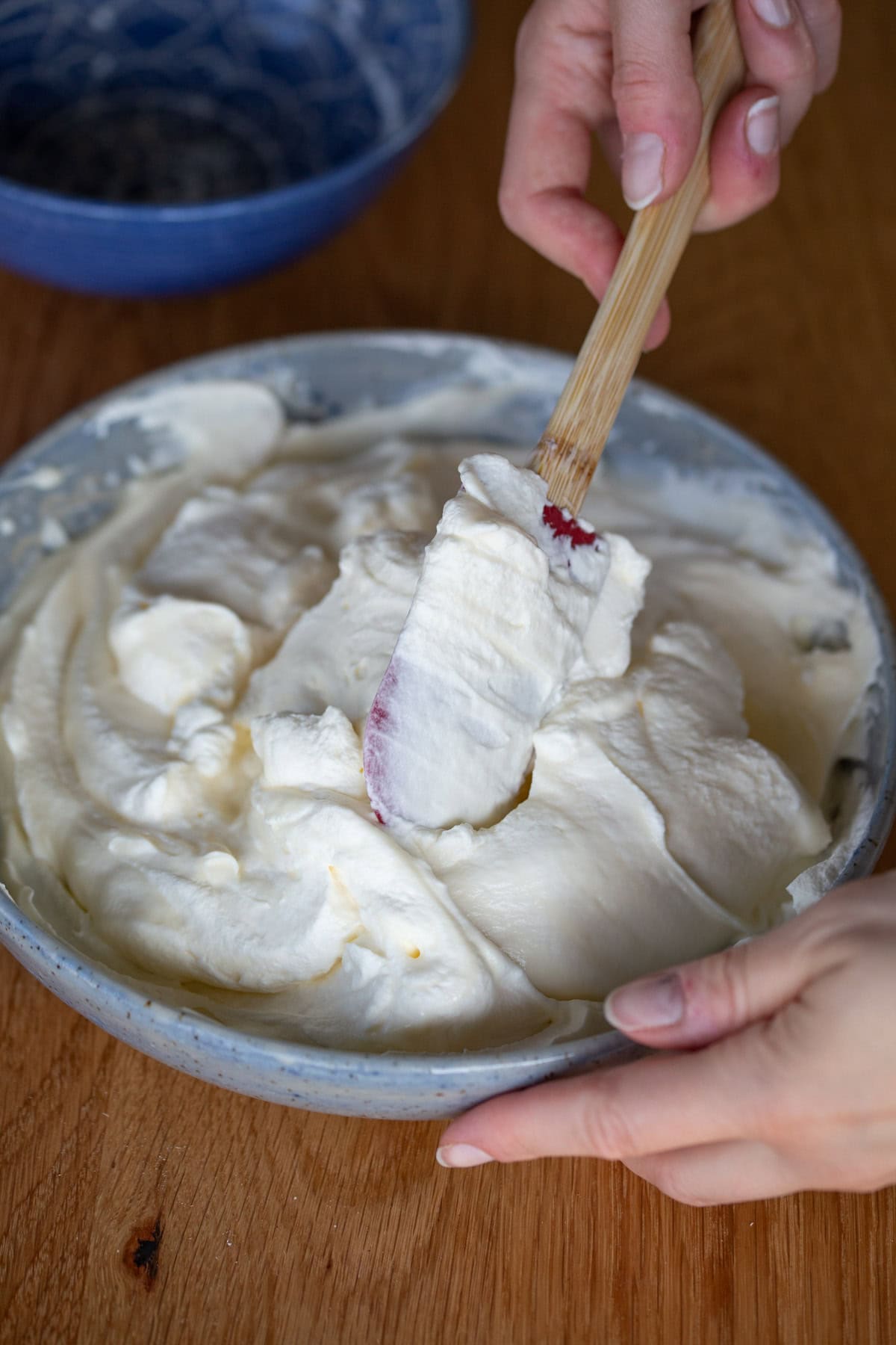 Folding whipped cream into mascarpone cream with a spatula.