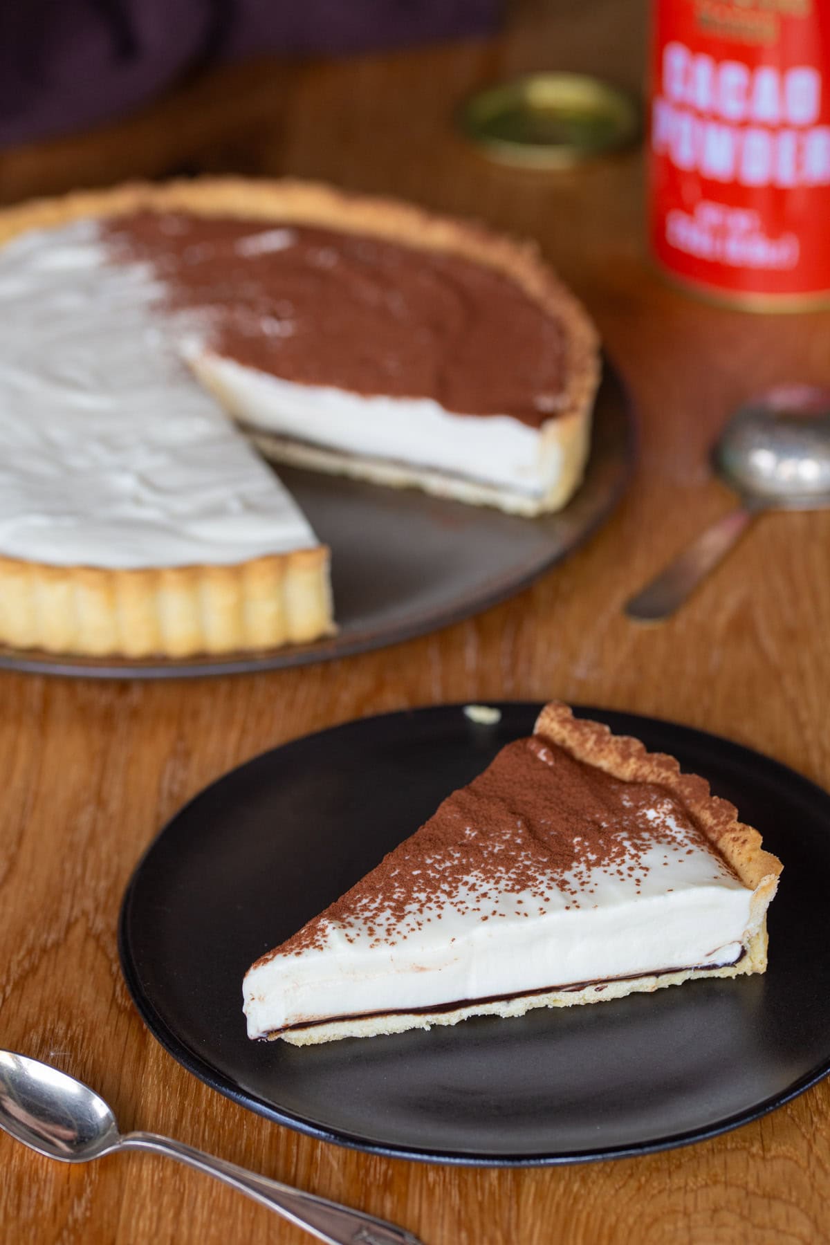 Slice of tiramisu pie, rest of the cake in the background.