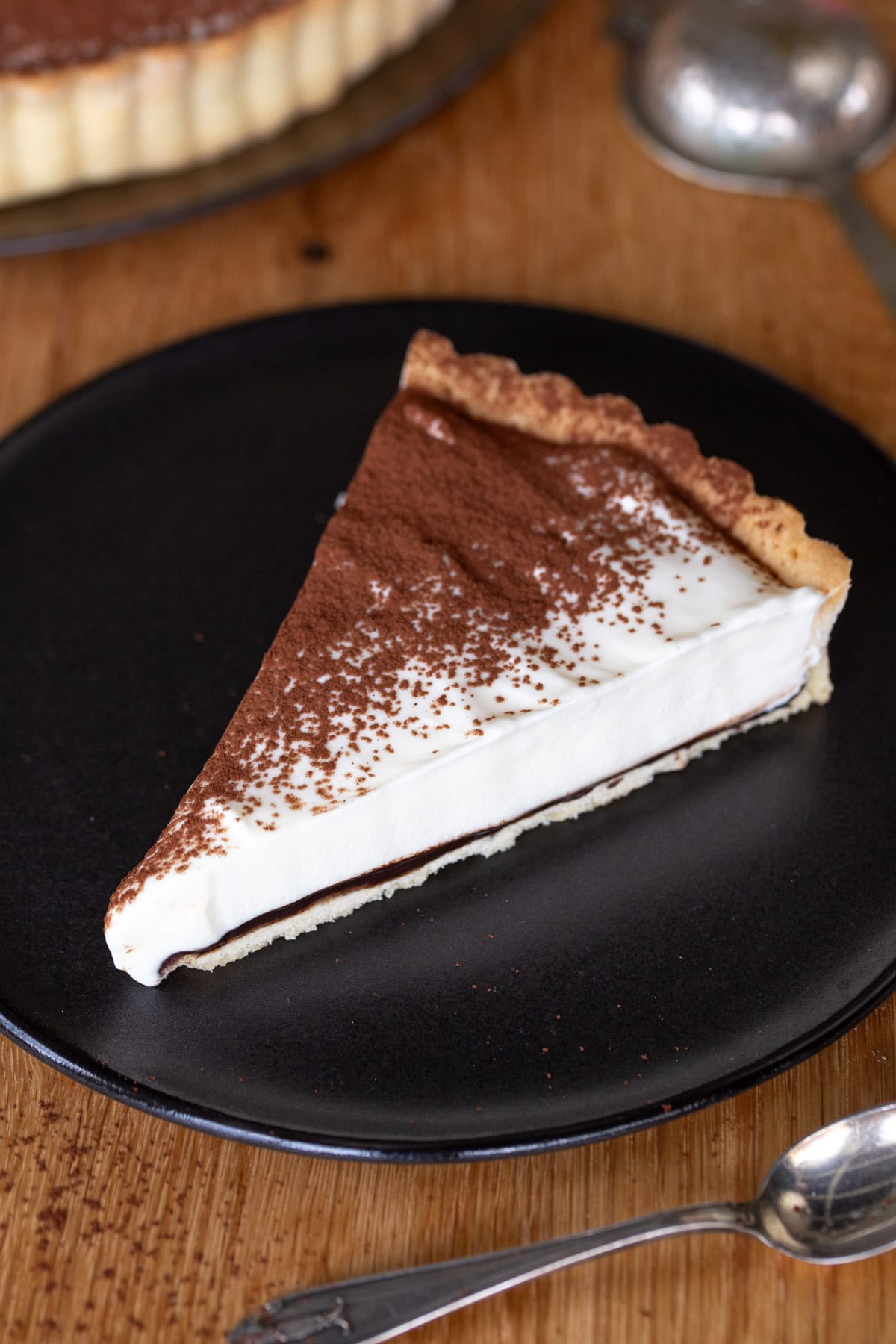 One slice of tiramisu pie on a dark plate.