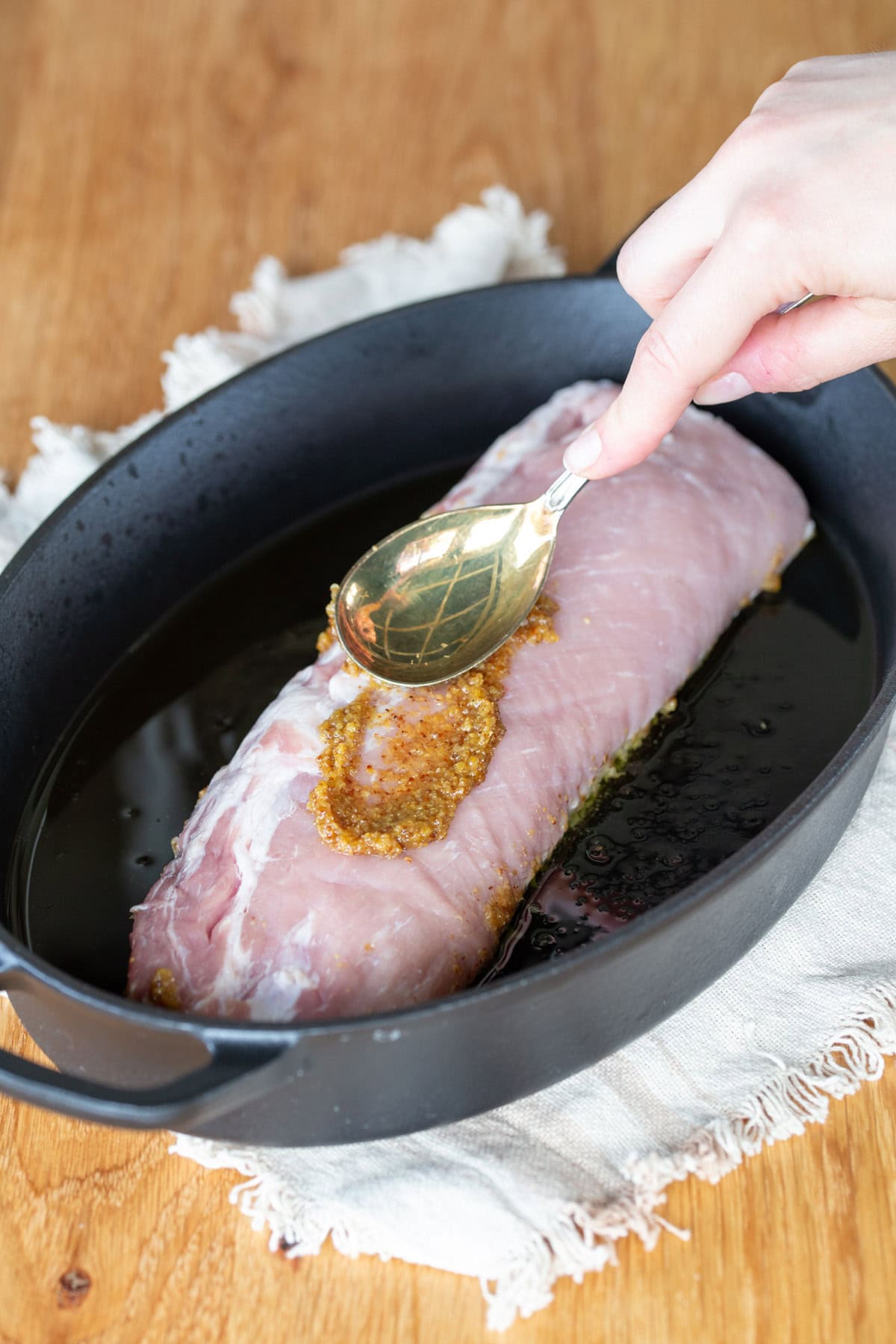 Spreading mustard over pork loin.
