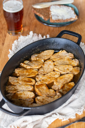 Baked pork loin with mustard and beer glaze in a cast iron casserole dish.