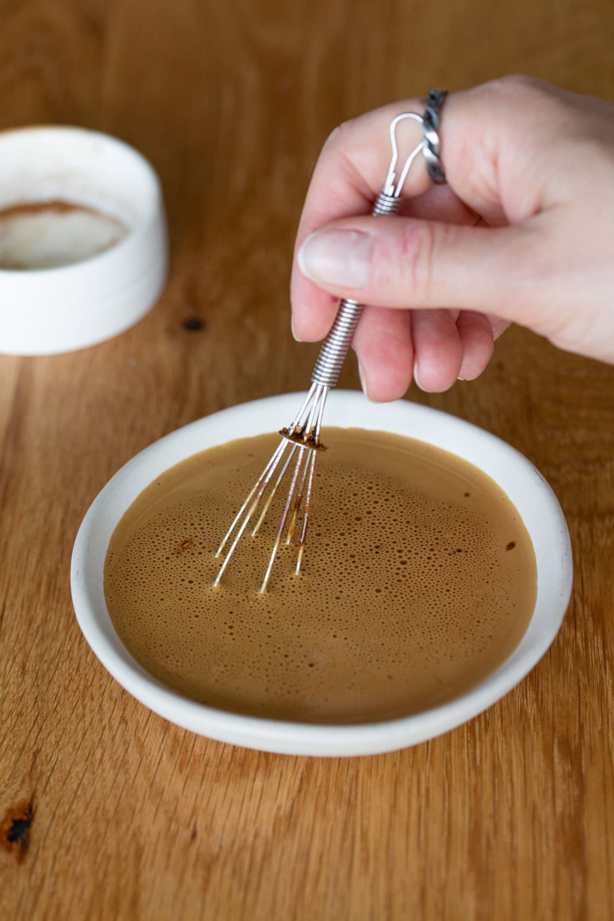 Small whisk stirring instant coffee in hot cream.
