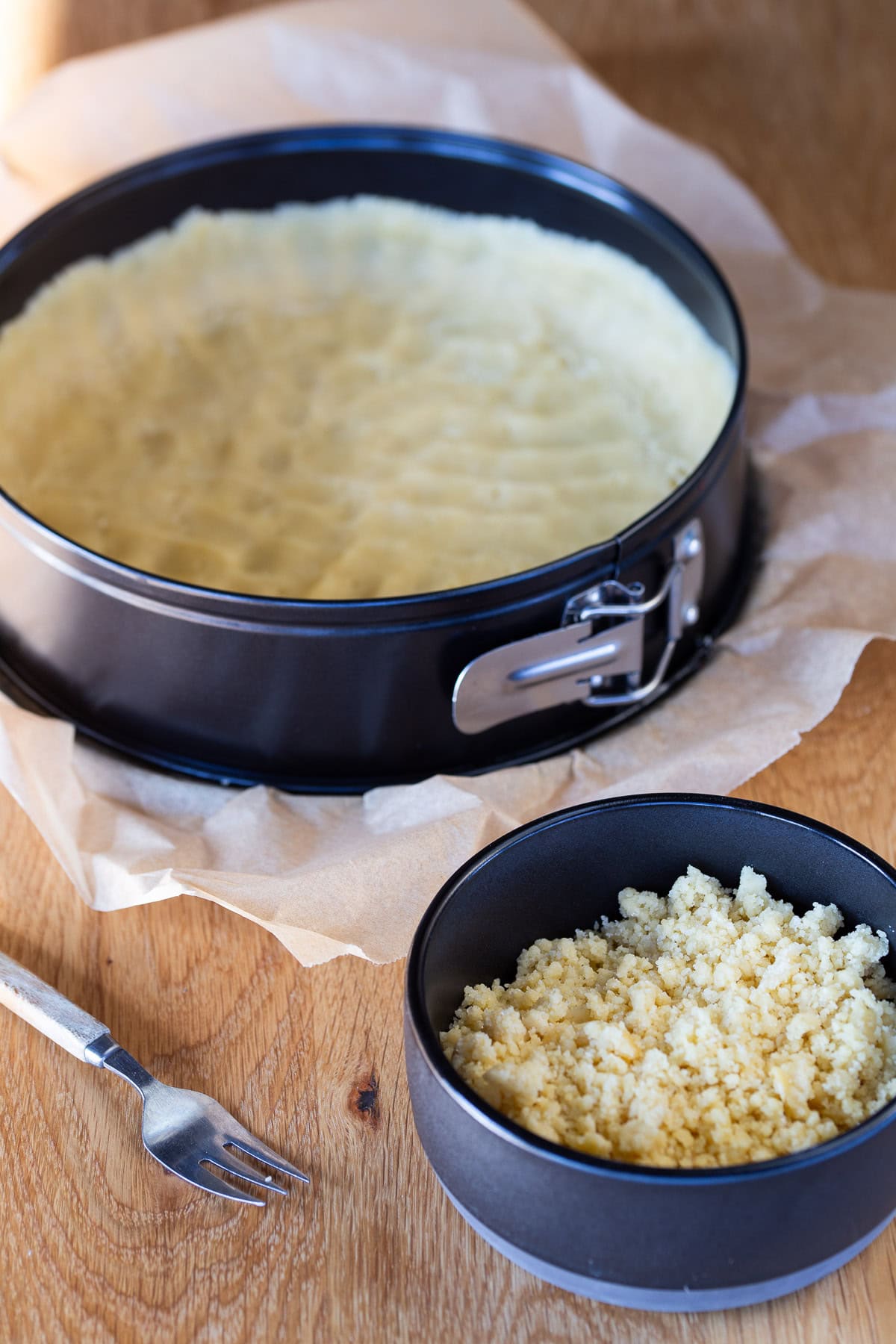 Pie dough pressed onto pan and part of it, crumbly, aside in a bowl.