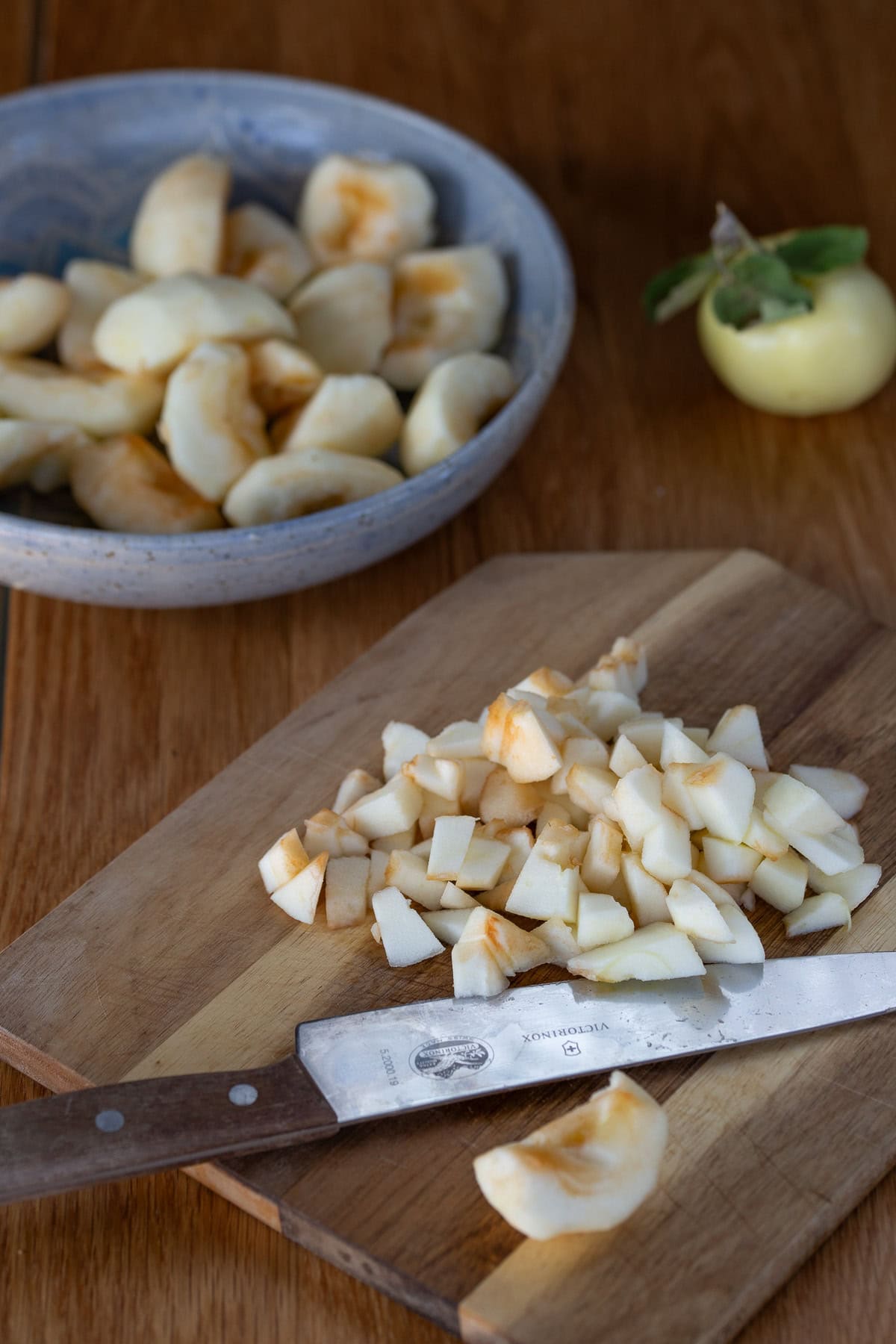 Apples being sliced on wooden cutting board.