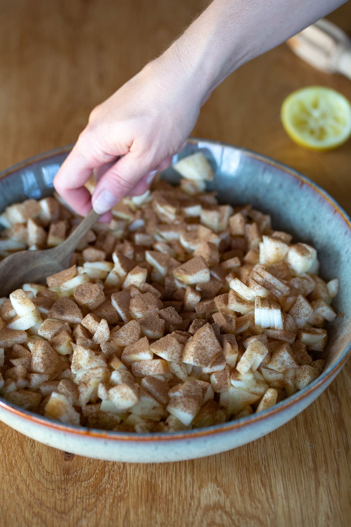 Hand stirring cinnamon into diced raw apples.
