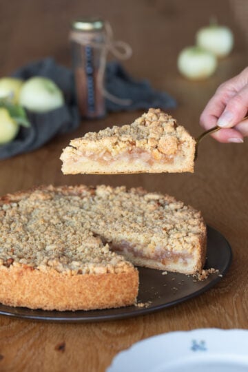Hand lifting a slice of szarlotka Polish apple pie.