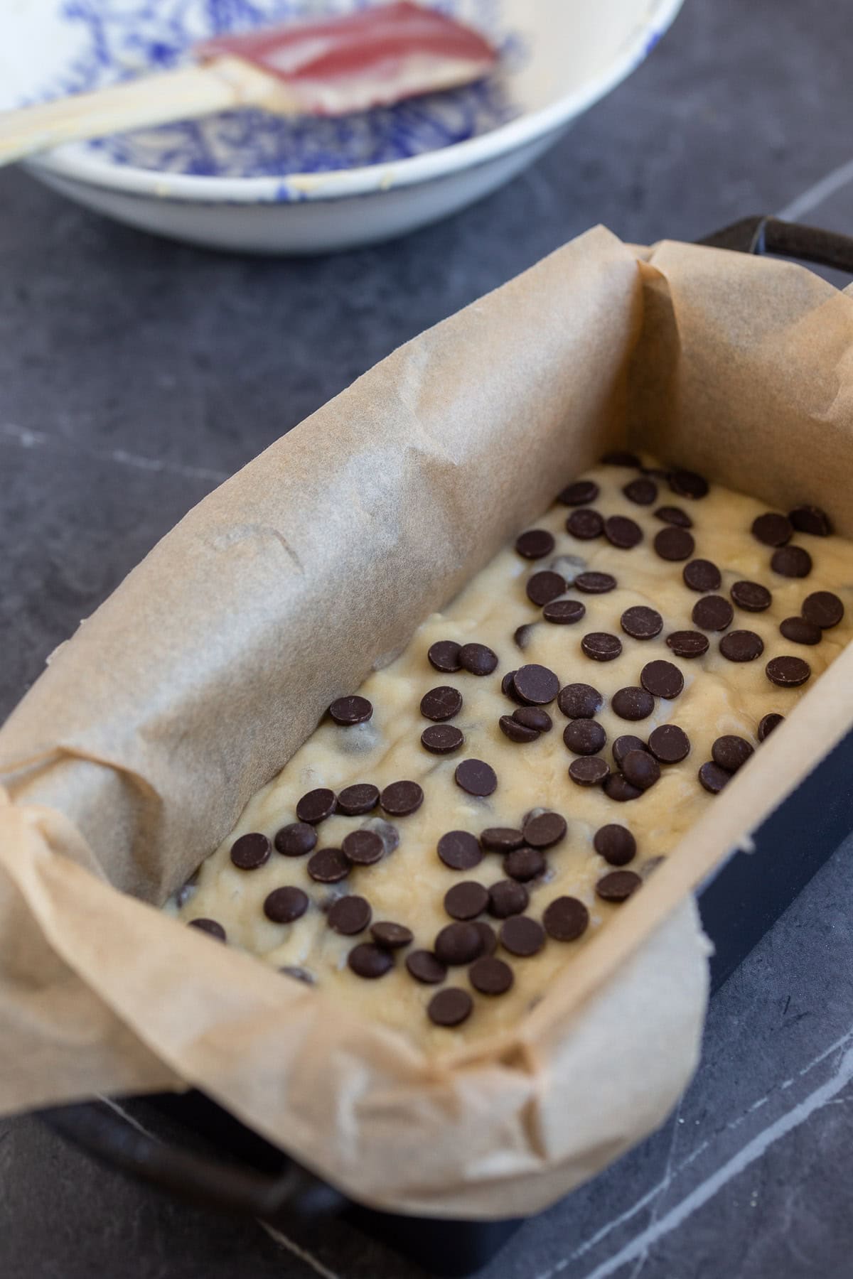 Raw batter in a loaf pan lined with baking paper.