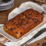 Banana bread with chocolate chips on a white serving plate.