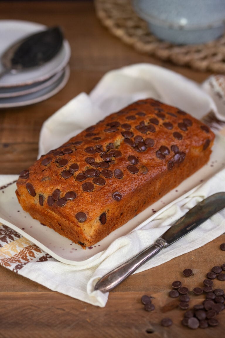 Banana bread with chocolate chips on a white serving plate.