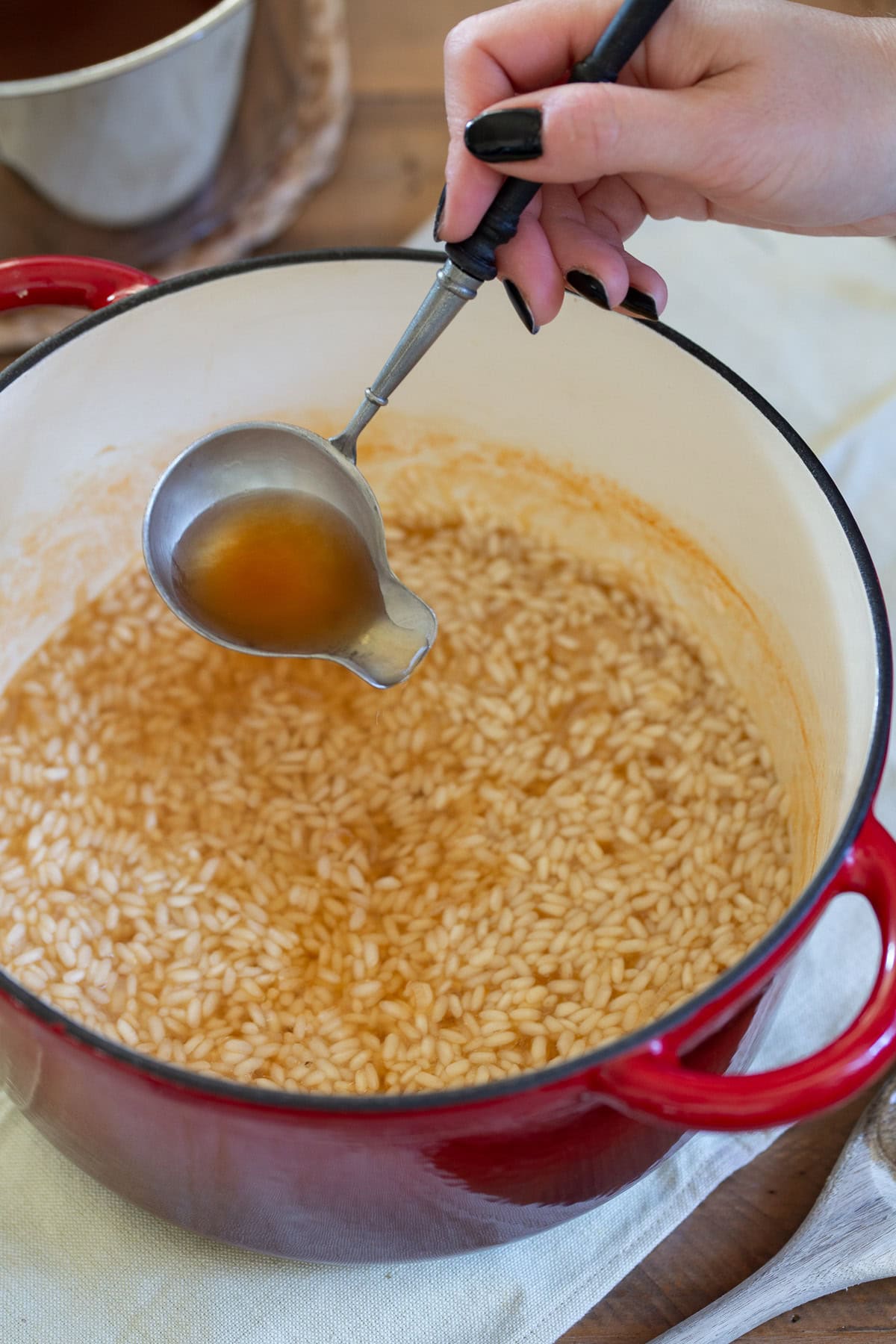 Adding broth to risotto with a ladle.