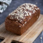 A loaf of multigrain bread on a wooden board.