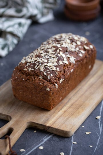 A loaf of multigrain bread on a wooden board.