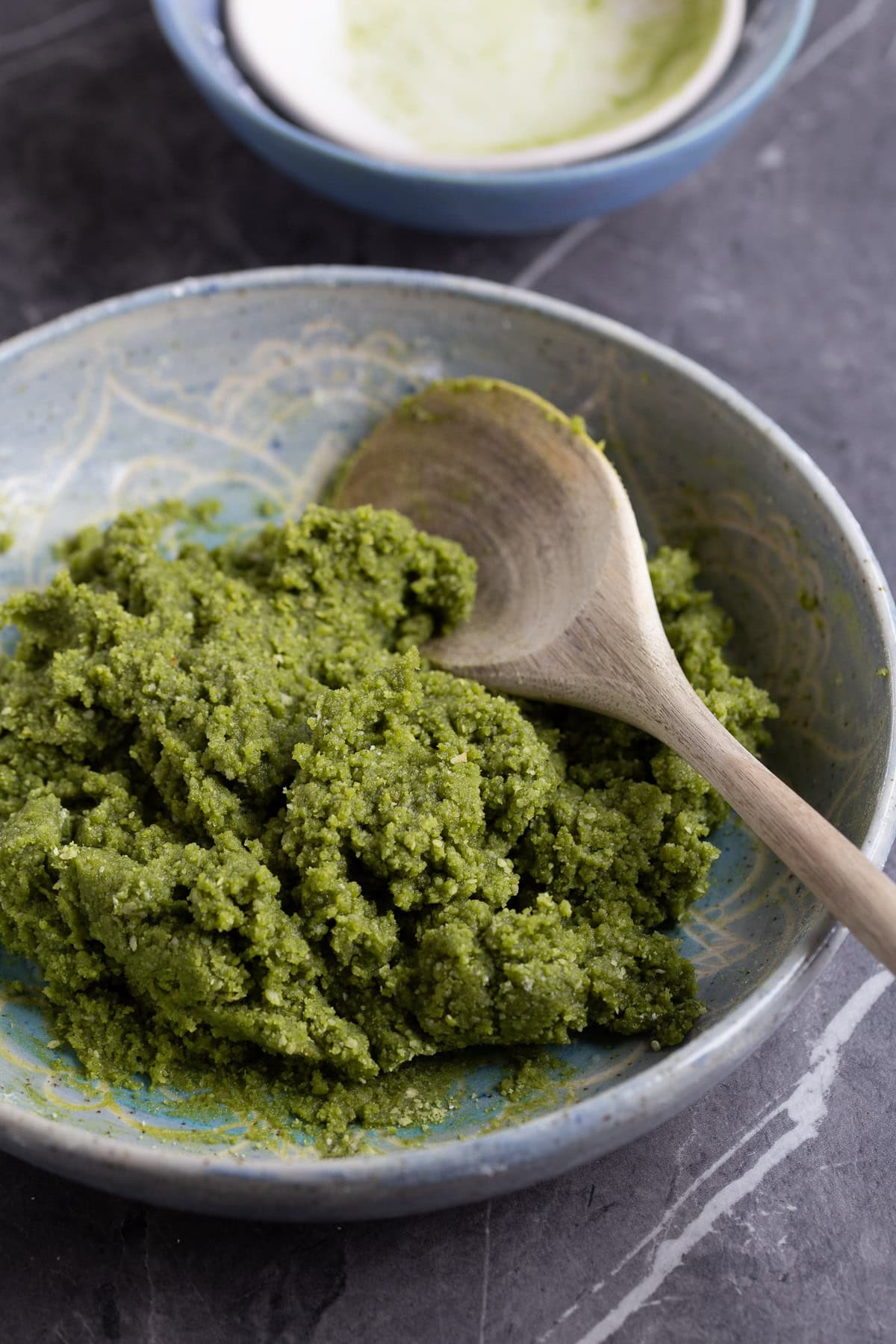 Almond paste with matcha powder in a light blue bowl.