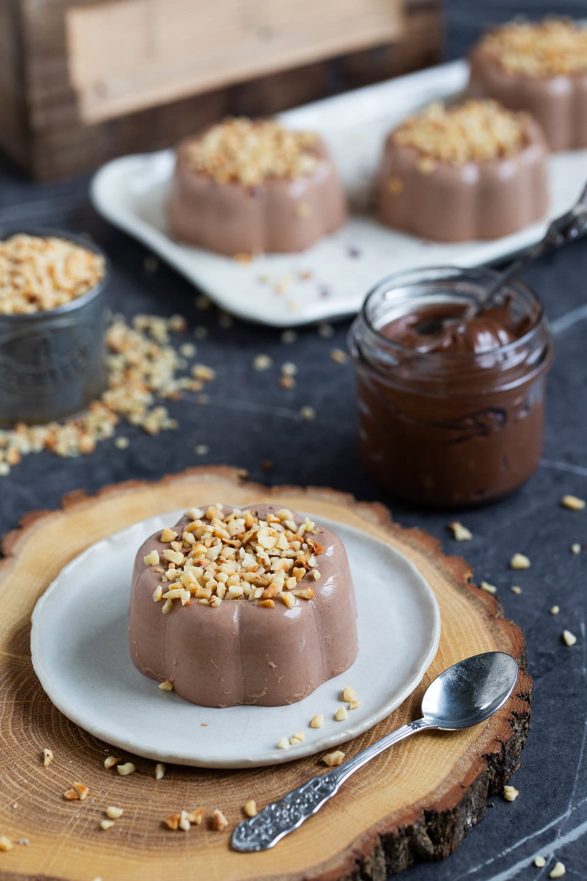 Nutella panna cotta topped with chopped hazelnuts, served on a small white plate.