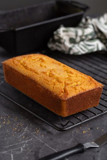A loaf of polenta cornbread on a cooling rack.
