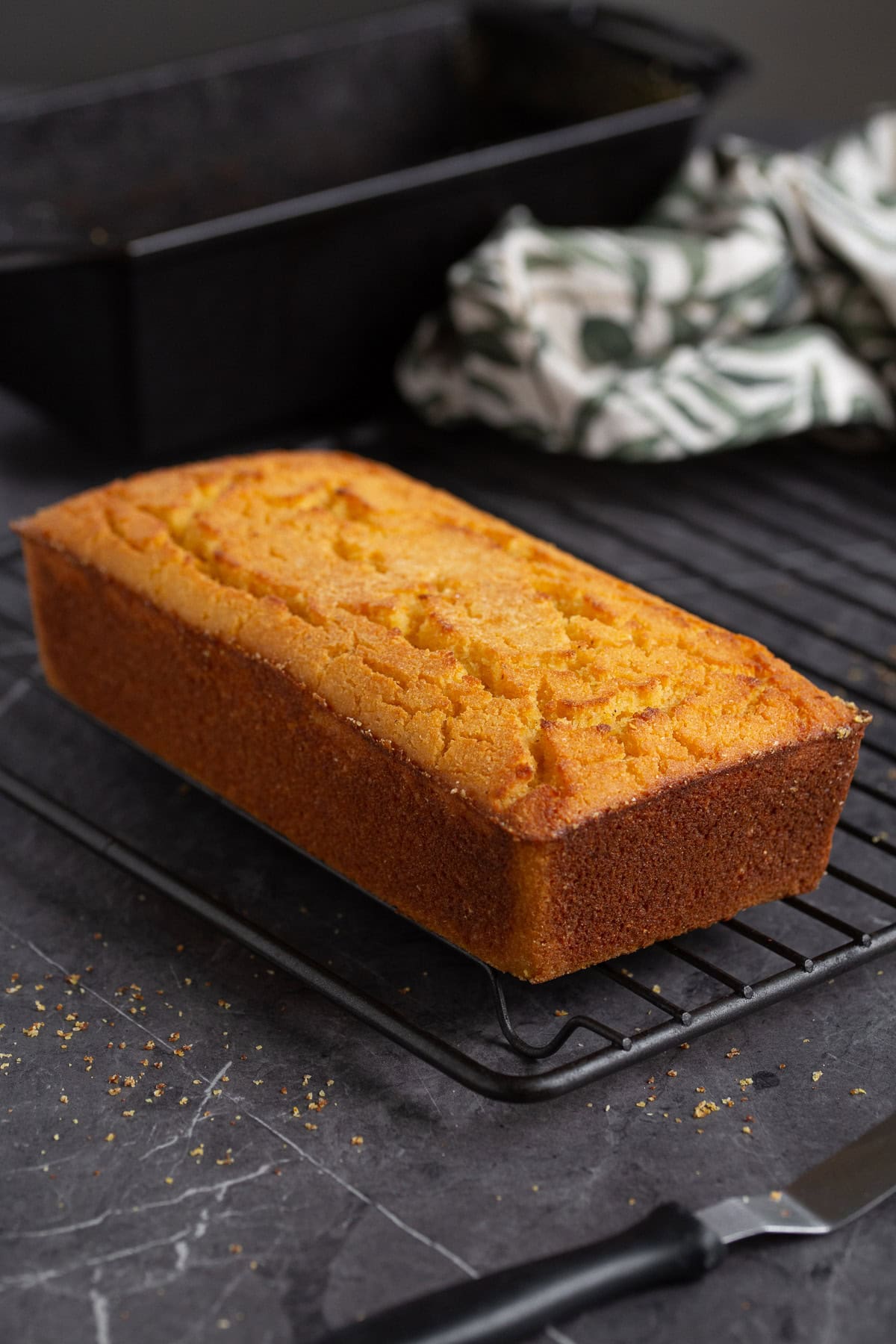 A loaf of polenta cornbread on a cooling rack.