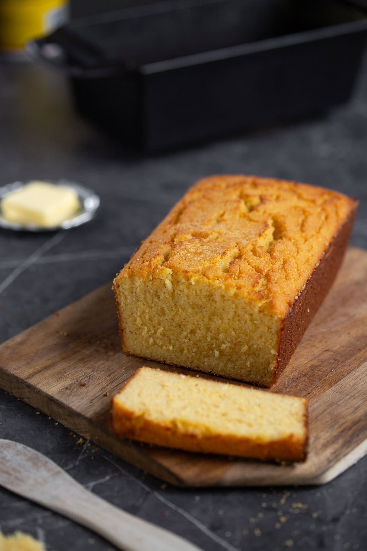 Cornbread sliced on a wooden cutting board.